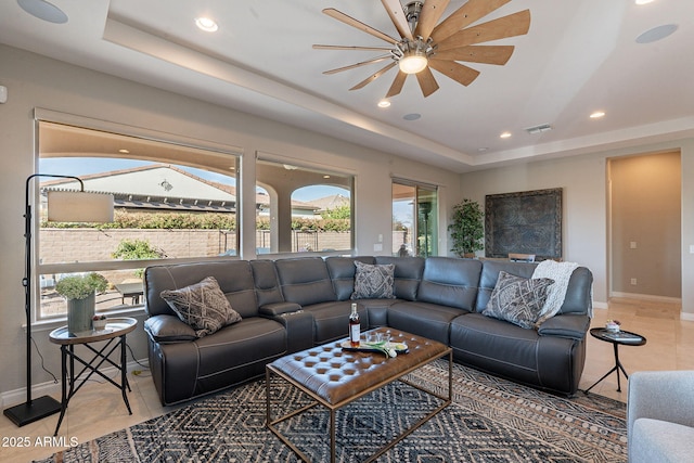 living room featuring a raised ceiling, light tile patterned flooring, baseboards, and visible vents