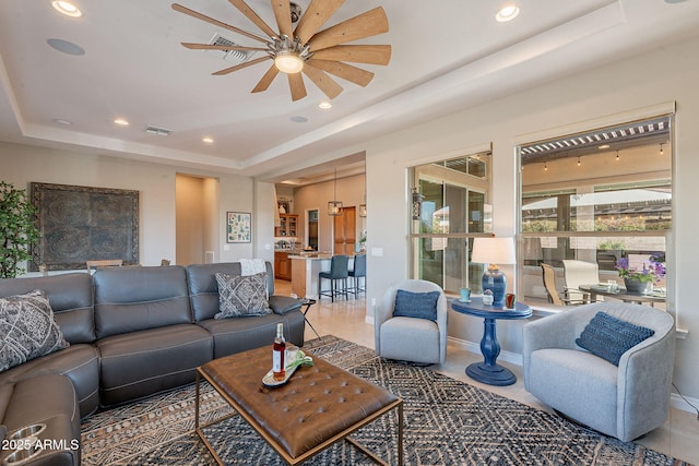 living room featuring recessed lighting, visible vents, a raised ceiling, and a ceiling fan