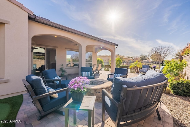 view of patio / terrace with an outdoor living space with a fire pit, ceiling fan, and fence