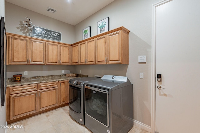 clothes washing area featuring visible vents, cabinet space, and separate washer and dryer