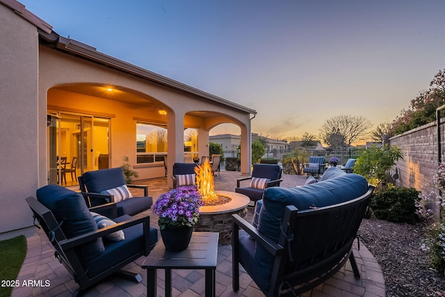 patio terrace at dusk with an outdoor living space with a fire pit and fence private yard