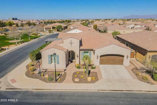 mediterranean / spanish-style home with a residential view, driveway, and a tiled roof