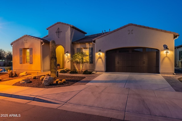 mediterranean / spanish house featuring concrete driveway, a tiled roof, an attached garage, and stucco siding