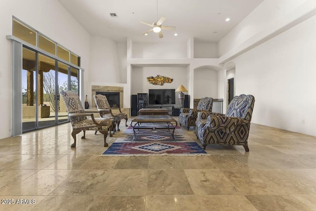 living area with visible vents, a towering ceiling, and ceiling fan