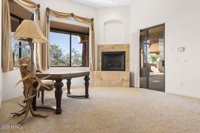 living area with a tiled fireplace, plenty of natural light, and carpet floors