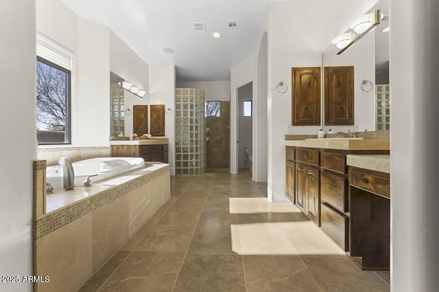 full bath featuring vanity, a garden tub, visible vents, and walk in shower