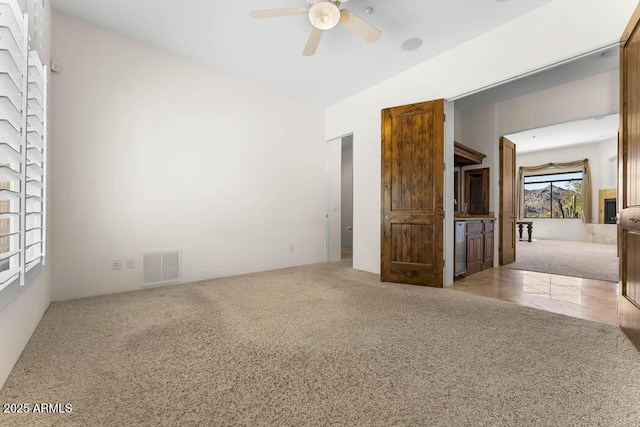 carpeted empty room featuring visible vents and ceiling fan