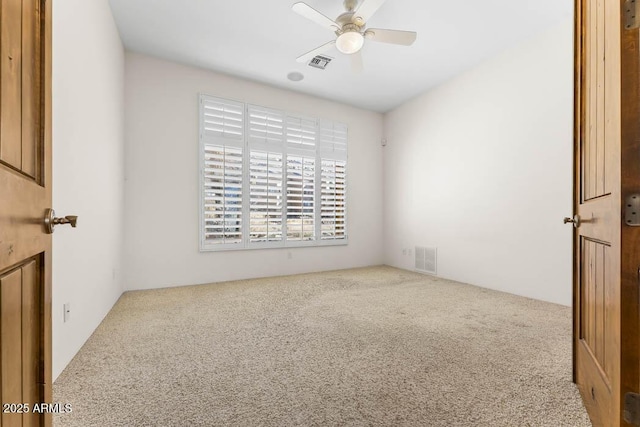 carpeted empty room with visible vents and a ceiling fan