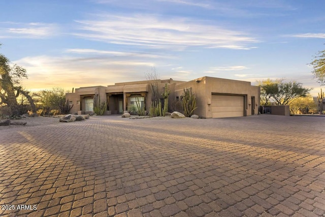 pueblo-style home with a garage and stucco siding