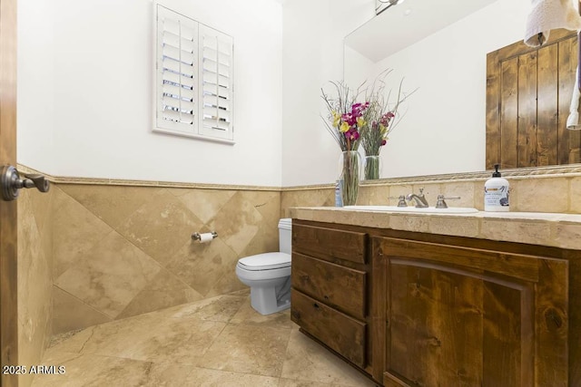 bathroom with vanity, a wainscoted wall, tile walls, toilet, and tile patterned floors