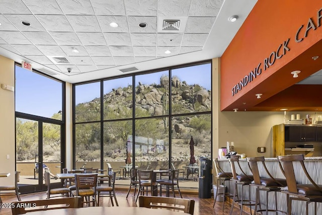 interior space with expansive windows, plenty of natural light, visible vents, and wood finished floors