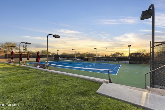 view of sport court with a lawn and fence