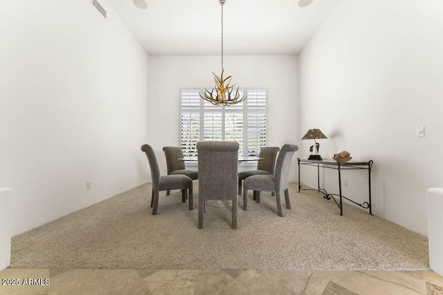 carpeted dining room featuring visible vents and an inviting chandelier