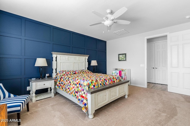 bedroom with ceiling fan, visible vents, light colored carpet, and a decorative wall