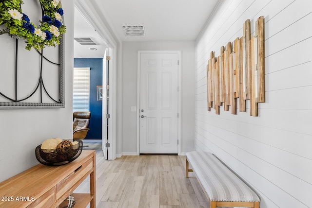 interior space featuring wood walls, light wood finished floors, and visible vents