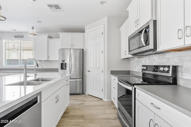 kitchen featuring white cabinets, visible vents, stainless steel appliances, and a sink