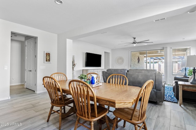 dining area with light wood finished floors, baseboards, visible vents, and ceiling fan