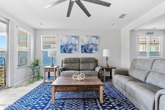 living room with baseboards, a ceiling fan, and visible vents
