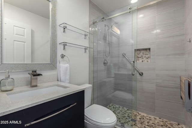 bathroom featuring vanity, a shower with door, and toilet