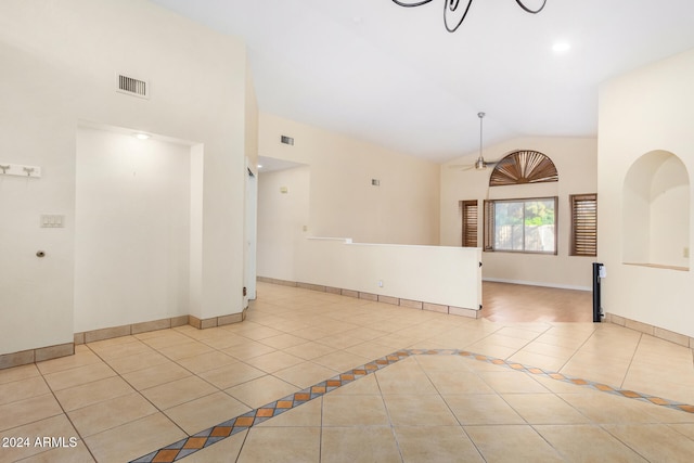 tiled empty room featuring high vaulted ceiling and a notable chandelier