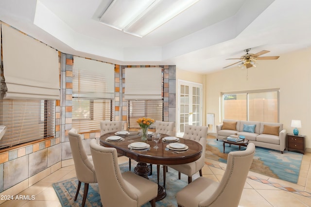 tiled dining area with a tray ceiling and ceiling fan