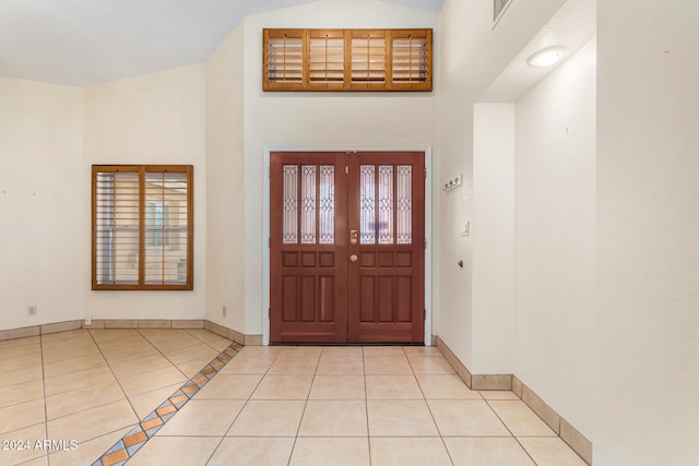 foyer featuring light tile patterned floors and high vaulted ceiling