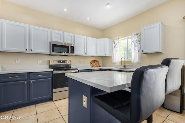 kitchen with sink, white cabinetry, appliances with stainless steel finishes, light tile patterned floors, and blue cabinets