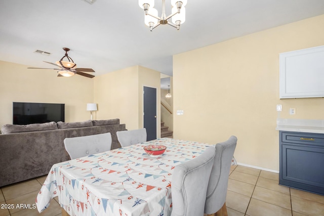 tiled dining room featuring ceiling fan with notable chandelier