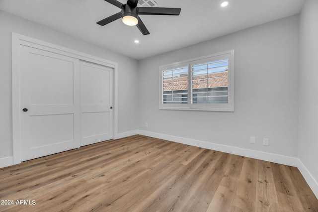 unfurnished bedroom with ceiling fan, a closet, and light hardwood / wood-style flooring