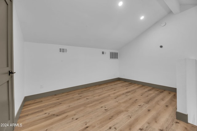 unfurnished room featuring lofted ceiling with beams and light hardwood / wood-style flooring