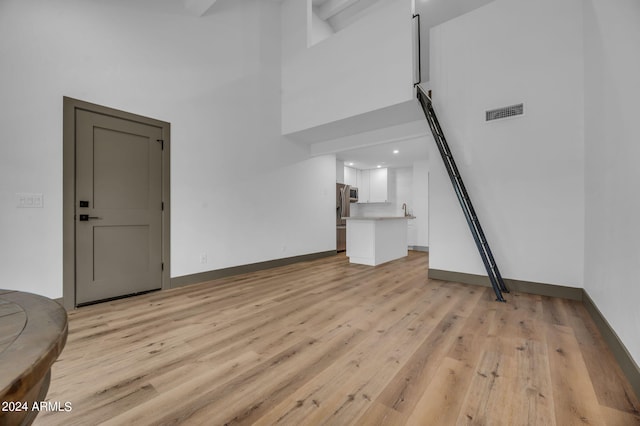 living room with a high ceiling and light hardwood / wood-style flooring