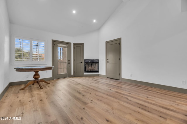 foyer with a multi sided fireplace, high vaulted ceiling, and light hardwood / wood-style floors