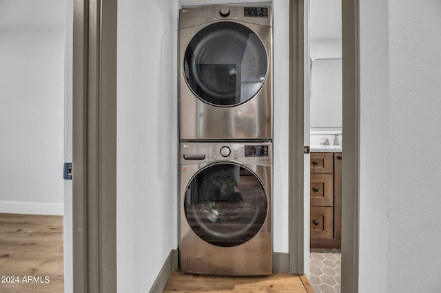 clothes washing area featuring light wood-type flooring and stacked washer / dryer