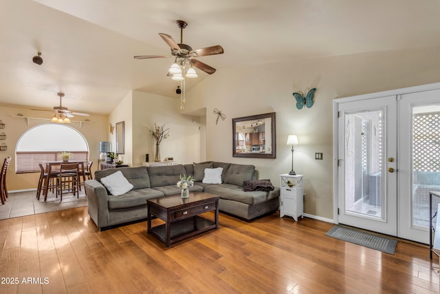 living room featuring hardwood / wood-style flooring, ceiling fan, vaulted ceiling, and french doors