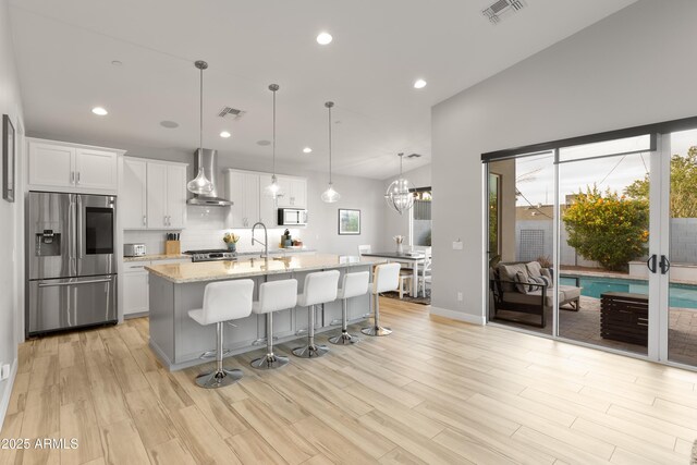 6450 E Vernon Ave, Scottsdale, AZ 85257 - kitchen featuring stainless steel refrigerator with ice dispenser, wall chimney range hood, white microwave, an island with sink, and a kitchen breakfast bar