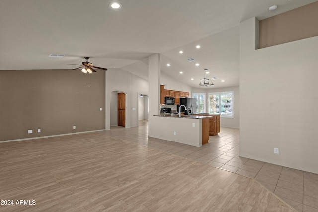 kitchen with light wood-type flooring, sink, high vaulted ceiling, stainless steel refrigerator with ice dispenser, and ceiling fan with notable chandelier