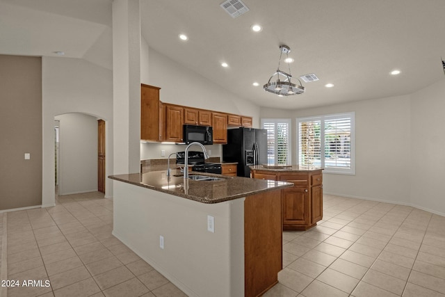 kitchen featuring dark stone countertops, a notable chandelier, sink, black appliances, and a center island