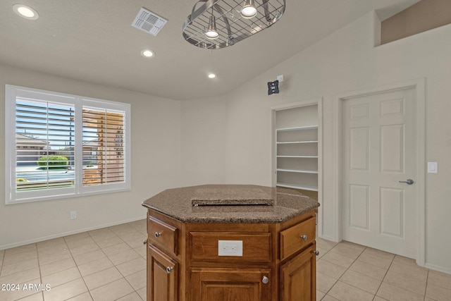 kitchen featuring lofted ceiling, dark stone counters, light tile patterned flooring, and a center island