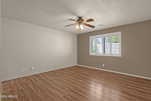 empty room with ceiling fan, hardwood / wood-style flooring, and a textured ceiling