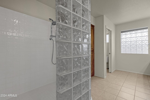 bathroom with tile patterned floors, tiled shower, and a textured ceiling