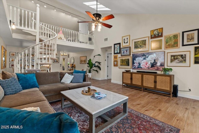 living area with visible vents, stairs, wood finished floors, baseboards, and ceiling fan