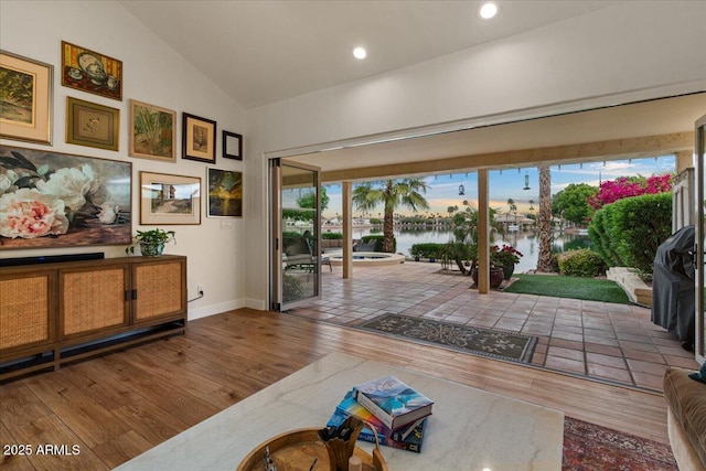doorway to outside featuring wood-type flooring, recessed lighting, baseboards, a water view, and vaulted ceiling
