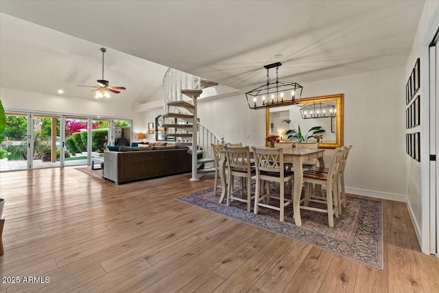 dining area with stairs, wood finished floors, lofted ceiling, baseboards, and ceiling fan with notable chandelier