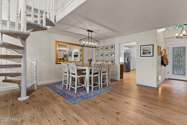 dining space featuring wood finished floors, a chandelier, and stairway