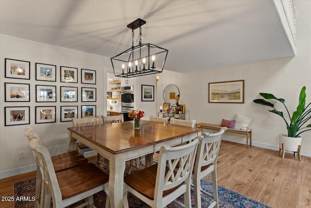 dining area featuring baseboards, a notable chandelier, and wood finished floors