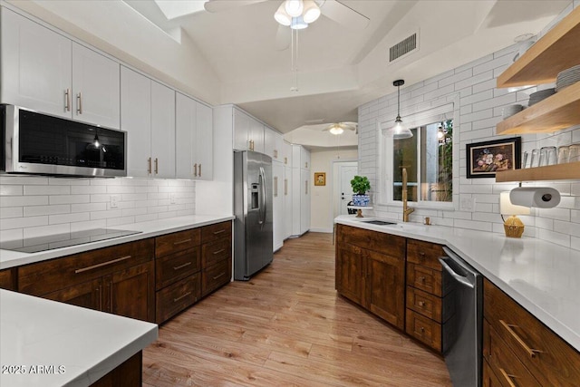 kitchen featuring white cabinets, appliances with stainless steel finishes, a ceiling fan, decorative backsplash, and visible vents