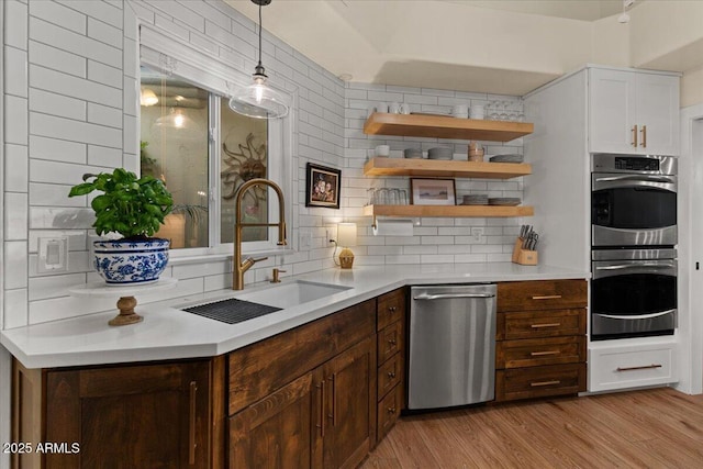 kitchen featuring light countertops, stainless steel appliances, a sink, and light wood-style floors