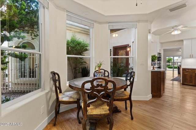 dining space featuring visible vents, light wood-style floors, ceiling fan, and baseboards