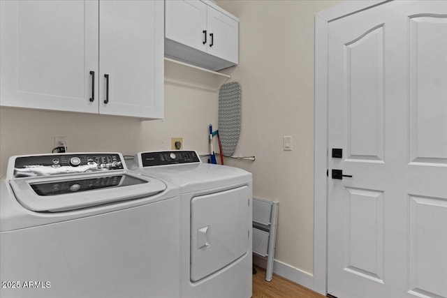 laundry room featuring independent washer and dryer, baseboards, light wood-type flooring, and cabinet space