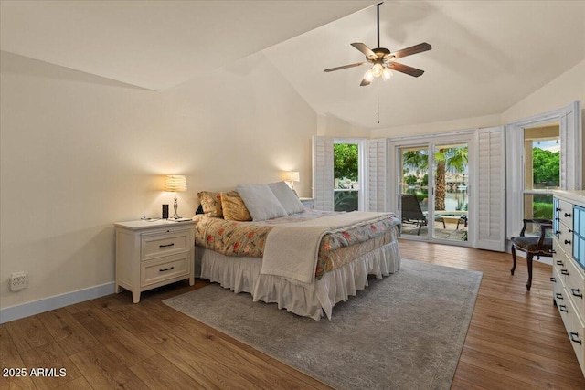 bedroom featuring wood finished floors, vaulted ceiling, multiple windows, and access to exterior